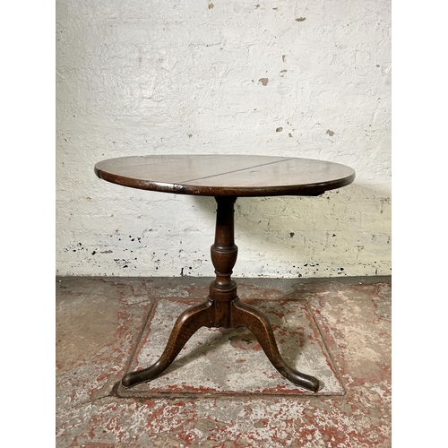 40 - A George III oak circular tilt top tripod occasional table - approx. 114cm high x 78cm in diameter