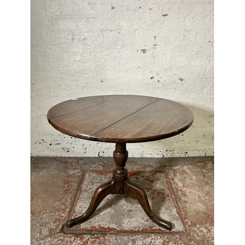 40 - A George III oak circular tilt top tripod occasional table - approx. 114cm high x 78cm in diameter