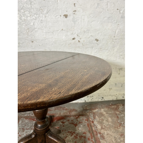 40 - A George III oak circular tilt top tripod occasional table - approx. 114cm high x 78cm in diameter