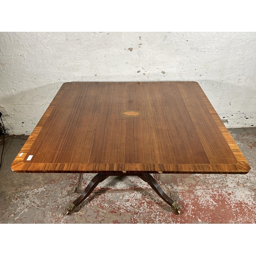 86 - An early 20th century Georgian style inlaid mahogany dining table on quatrefoil base and brass lion ... 