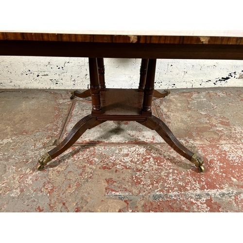 86 - An early 20th century Georgian style inlaid mahogany dining table on quatrefoil base and brass lion ... 