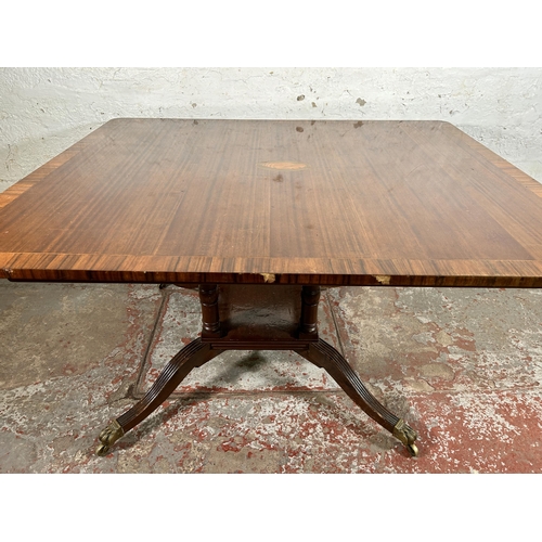 86 - An early 20th century Georgian style inlaid mahogany dining table on quatrefoil base and brass lion ... 