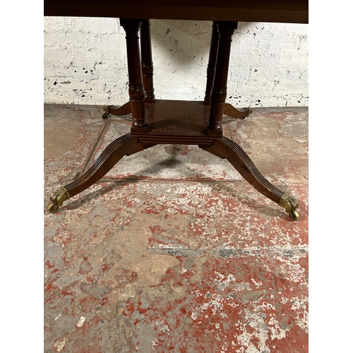 86 - An early 20th century Georgian style inlaid mahogany dining table on quatrefoil base and brass lion ... 