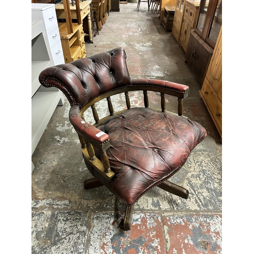 93 - An oxblood leather and mahogany captain's swivel desk chair