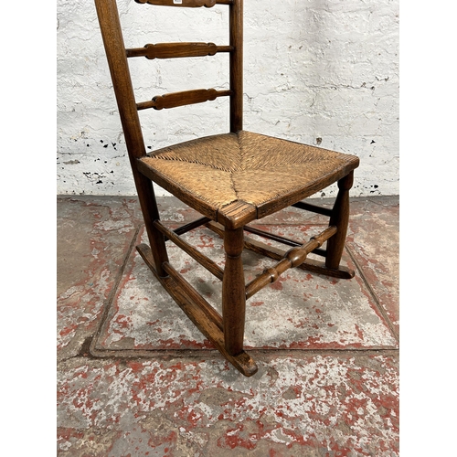 195 - A 19th century ash and elm rush seated ladder back rocking chair