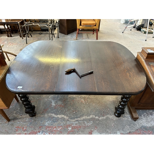 197 - A early 20th century oak wind out dining table on bobbin turned supports and castors - approx. 72cm ... 