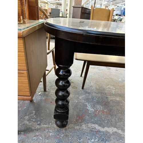 197 - A early 20th century oak wind out dining table on bobbin turned supports and castors - approx. 72cm ... 