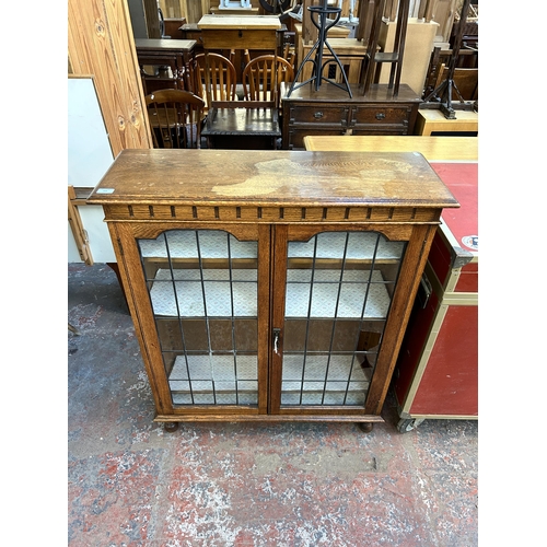 209 - An early 20th century oak display cabinet with two lead glazed doors