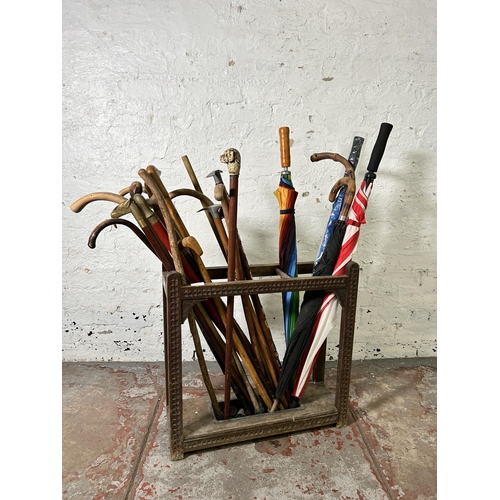 235 - An early 20th century carved oak three section stick stand with black metal drip tray and a large co... 