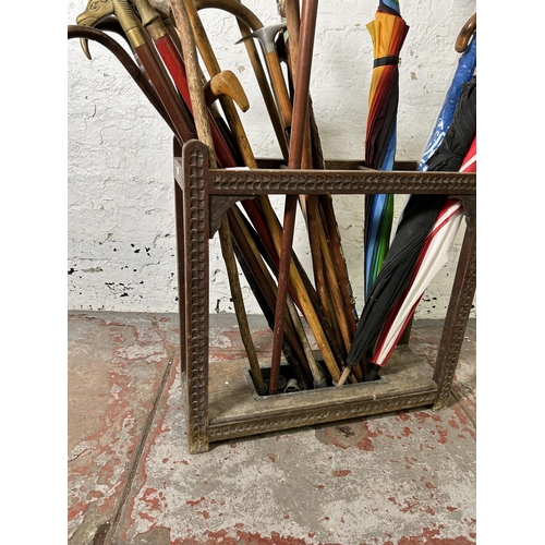 235 - An early 20th century carved oak three section stick stand with black metal drip tray and a large co... 