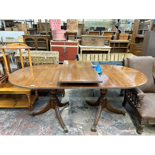 241 - A Regency style mahogany twin pedestal extending dining table on brass lion paw supports and casters