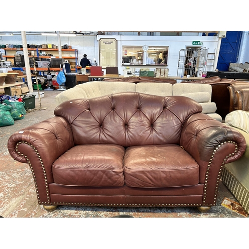 250 - A burgundy leather button back two seater sofa on turned wooden supports