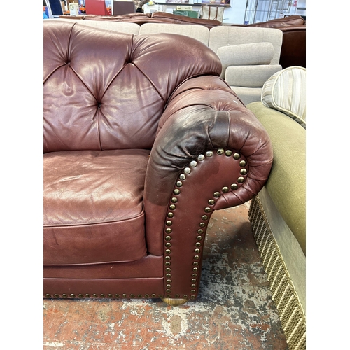 250 - A burgundy leather button back two seater sofa on turned wooden supports