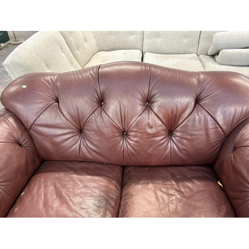 250 - A burgundy leather button back two seater sofa on turned wooden supports