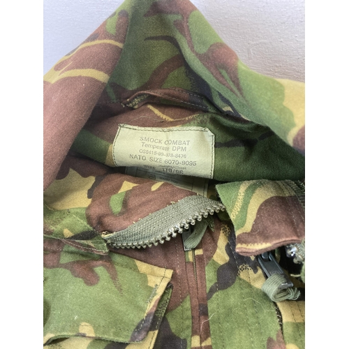 551 - Four pieces of military woodland camo clothing, two pairs of trousers, one shirt and one Smok combat... 