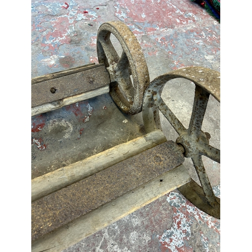 150A - Two pairs of antique cast iron wheels on wooden axles - largest approx. 101cm wide x 32cm diameter