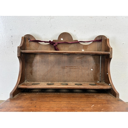 672 - An early 20th century mahogany wall mountable smoker's cabinet with five pipe holders and single dra... 