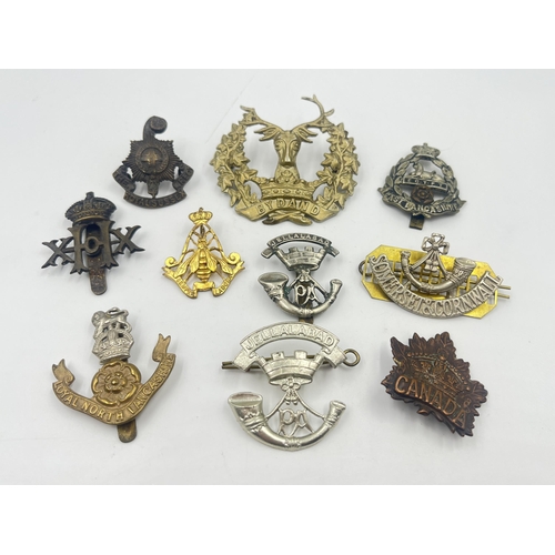 2239 - Ten military cap badges to include Loyal North Lancashire, East Lancashire, Canada, The Royal Sussex... 