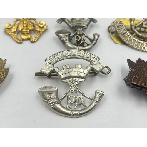 2239 - Ten military cap badges to include Loyal North Lancashire, East Lancashire, Canada, The Royal Sussex... 