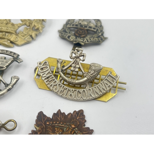 2239 - Ten military cap badges to include Loyal North Lancashire, East Lancashire, Canada, The Royal Sussex... 