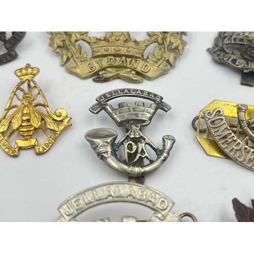 2239 - Ten military cap badges to include Loyal North Lancashire, East Lancashire, Canada, The Royal Sussex... 