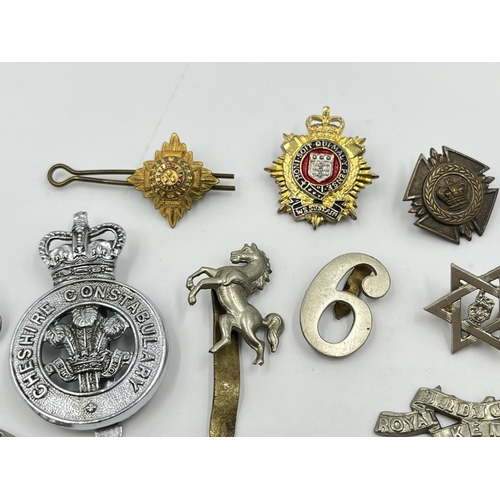 2261 - A collection of military and police cap badges to include Royal Fiji Police, Royal Kent West, Cheshi... 