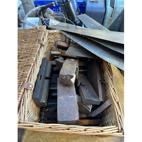 914 - A wicker basket containing a large collection of antique and later wood planes and hand saws