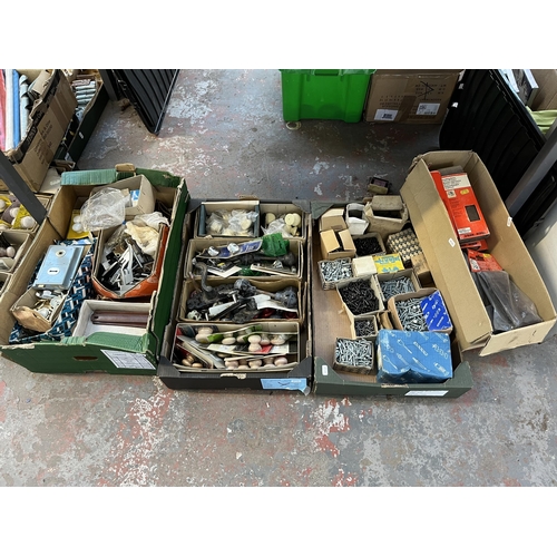 1037 - Seven boxes containing a large collection of door handles and knobs, drill bits, hinges, screws etc.