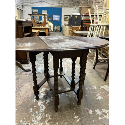 41 - An early 20th century oak drop leaf gate leg oval dining table on barley twist supports - approx. 72... 