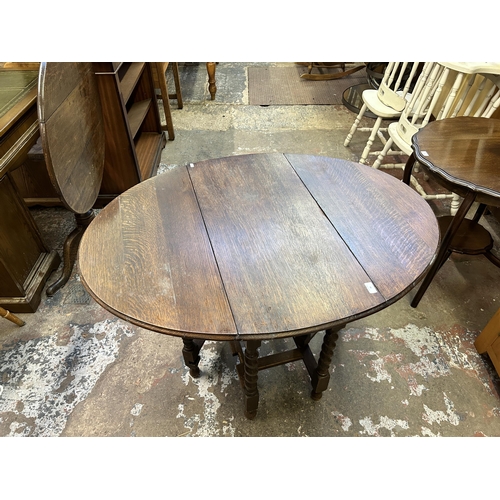 41 - An early 20th century oak drop leaf gate leg oval dining table on barley twist supports - approx. 72... 