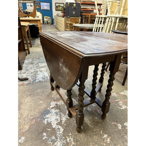 41 - An early 20th century oak drop leaf gate leg oval dining table on barley twist supports - approx. 72... 