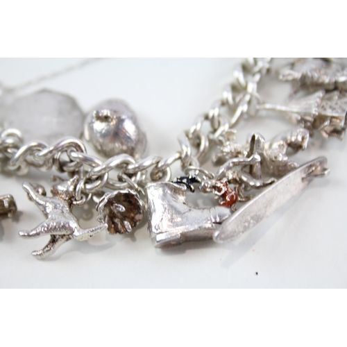 2074 - A silver charm bracelet with assorted charms - approx. gross weight 88g