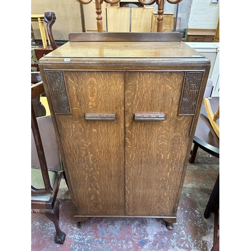 83 - An Art Deco style carved oak two door cabinet - approx. 138cm high x 76cm wide x 46cm deep