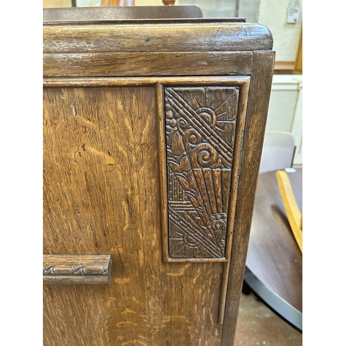 83 - An Art Deco style carved oak two door cabinet - approx. 138cm high x 76cm wide x 46cm deep