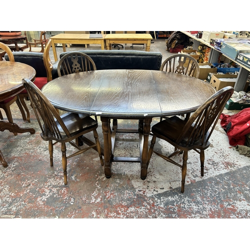 242 - An oak drop leaf gate leg dining table and four beech wheel back dining chairs