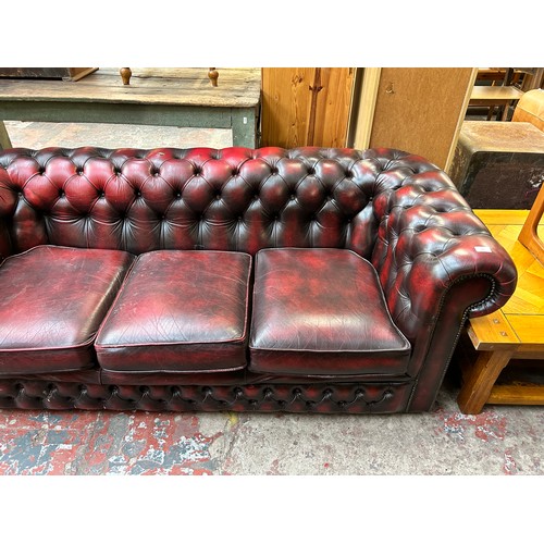 183 - An oxblood leather three seater Chesterfield sofa