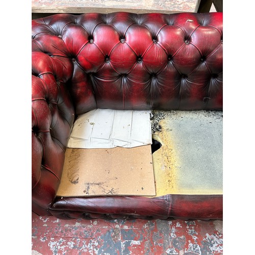 183 - An oxblood leather three seater Chesterfield sofa