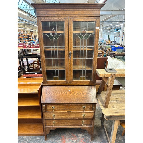 217 - An Arts and Crafts inlaid oak bureau bookcase with two stained and leaded glass doors - approx. 200c... 