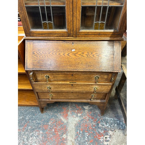 217 - An Arts and Crafts inlaid oak bureau bookcase with two stained and leaded glass doors - approx. 200c... 