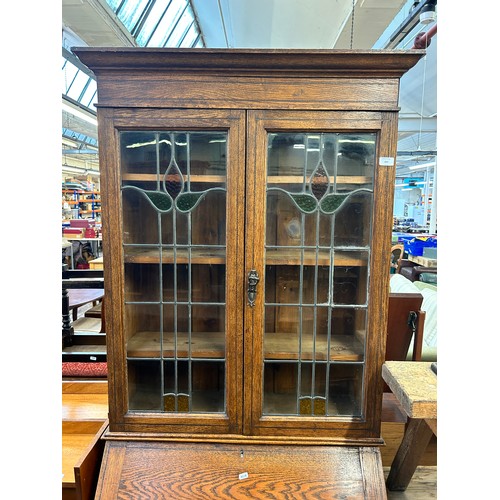 217 - An Arts and Crafts inlaid oak bureau bookcase with two stained and leaded glass doors - approx. 200c... 