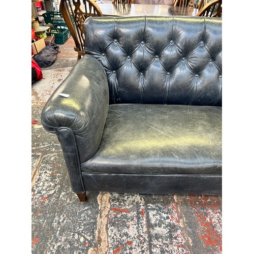 243 - A turn of the century blue leather button back upholstered two seater sofa stamped 