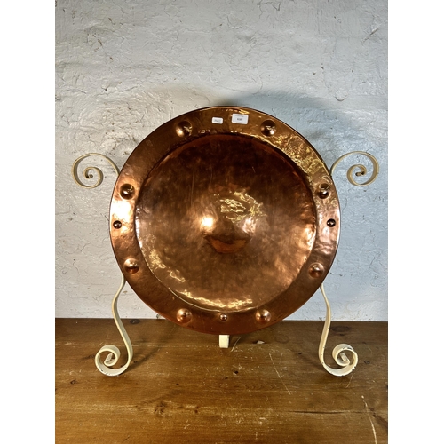 618 - A hammered and riveted copper wall charger in the manner of Wynyates Wear mounted on wrought iron st... 