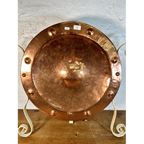 618 - A hammered and riveted copper wall charger in the manner of Wynyates Wear mounted on wrought iron st... 