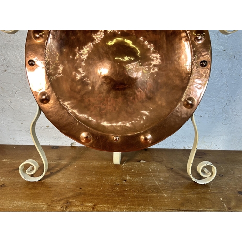 618 - A hammered and riveted copper wall charger in the manner of Wynyates Wear mounted on wrought iron st... 