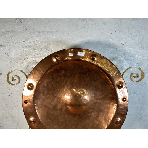 618 - A hammered and riveted copper wall charger in the manner of Wynyates Wear mounted on wrought iron st... 