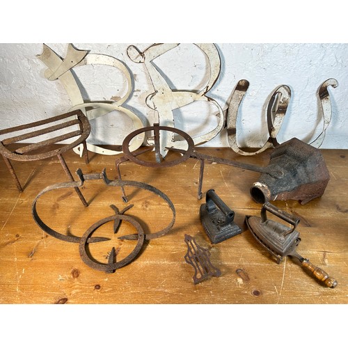 629 - A collection of antique and later metalware to include cast iron drain hopper, trivet stands, flat i... 