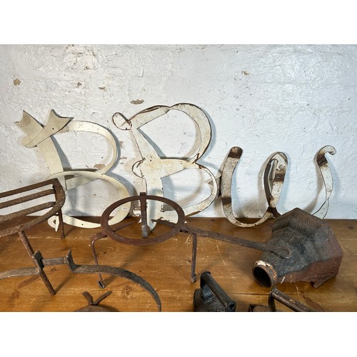 629 - A collection of antique and later metalware to include cast iron drain hopper, trivet stands, flat i... 