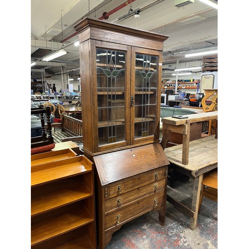 217 - An Arts and Crafts inlaid oak bureau bookcase with two stained and leaded glass doors - approx. 200c... 