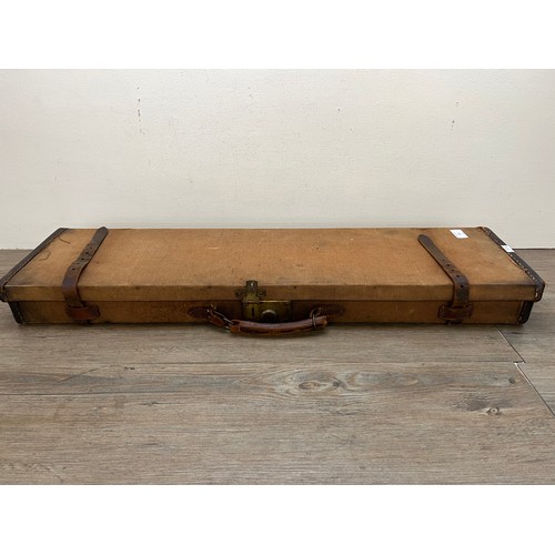 767 - A vintage canvas and leather shotgun case with baize lined interior compartments and oak and brass b... 