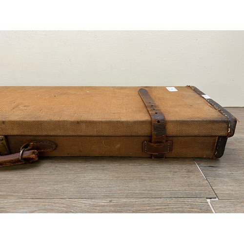 767 - A vintage canvas and leather shotgun case with baize lined interior compartments and oak and brass b... 